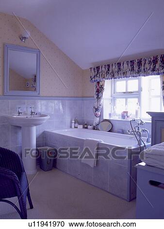 Stock Image - Tiled bath panel in country bathroom with wallpaper above dado-rail. Fotosearch