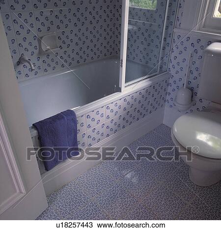 Stock Image - Tiled bath surround in modern blue+white tiled bathroom with contrasting blue+white tiled floor. Fotosearch
