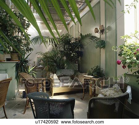 Stock Image - Traditional conservatory living room with comfortable furniture and green plants. Fotosearch