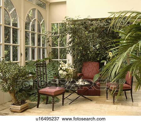 Stock Photo - Traditional conservatory living room with comfortable furniture and green plants. Fotosearch