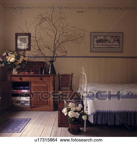 Picture - Traditional country bedroom with stencils, blue painted dado rail and iron bedstead.. Fotosearch