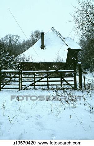 Stock Image - Traditional country cottage in snow in Winter. Fotosearch