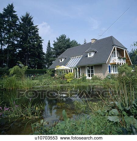 Traditional newbuild German house with balcony in large garden with natural pond View Large Photo Image Stock Image - Traditional newbuild German house with balcony in large garden with natural pond. Fotosearch
