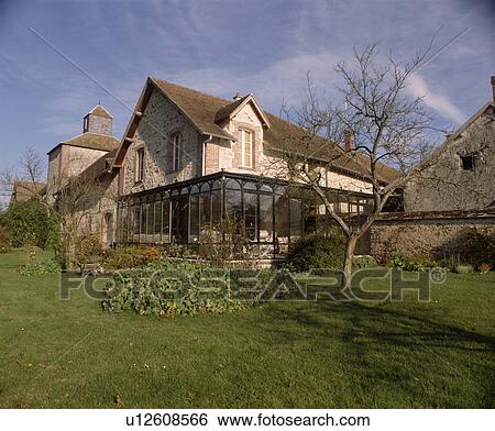 Stock Photograph - Traditional stone country house in France with glas conservatory extension. Fotosearch