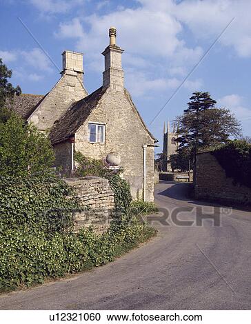 Stock Image - Traditional stone village house beside the road with church in the distance. Fotosearch