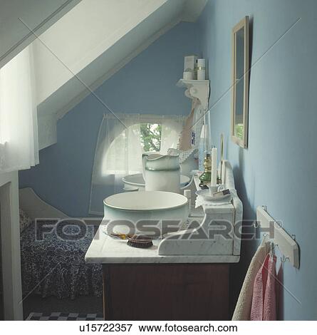 Traditional wash stand in a blue bedroom under the eaves of an attic conversion View Large Photo Image Stock Photo - Traditional wash stand in a blue bedroom under the eaves of an attic conversion. Fotosearch