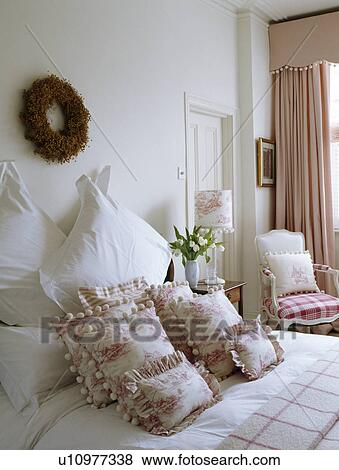 Twig wreath on wall above bed with pink Toile-de-Jouy cushions and white pillows View Large Photo Image Stock Photo - Twig wreath on wall above bed with pink Toile-de-Jouy cushions and white pillows. Fotosearch