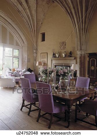 Stock Photo - Upholstered mauve chairs and antique table in country dining room with vaulted ceiling. Fotosearch