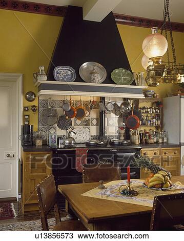Victorian style glass lamps over pine table and leather-backed chairs in traditional country kitchen with large black oven View Large Photo Image Stock Image - Victorian style glass lamps over pine table and leather-backed chairs in traditional country kitchen with large black oven. Fotosearch