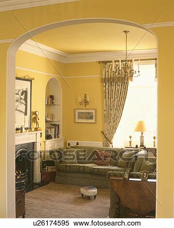 View through arch to green sofa in front of window in yellow livingroom View Large Photo Image Stock Photography - View through arch to green sofa in front of window in yellow livingroom. Fotosearch
