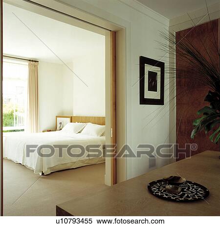 View through open doorway of modern white bedroom with cream carpet and white bedcover View Large Photo Image Stock Photography - View through open doorway of modern white bedroom with cream carpet and white bedcover. Fotosearch