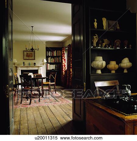 Stock Photography - View through open doorway of traditional townhouse dining room with antique furniture and wooden flooring. Fotosearch