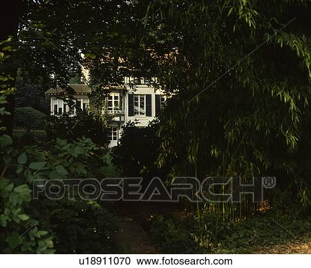 Stock Image - View through trees of white house. Fotosearch
