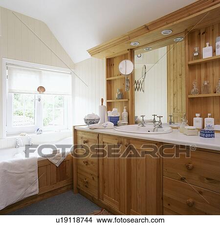 Picture - White basin built into large pine unit in white bathroom. Fotosearch