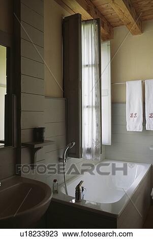 White bath below window with shutters in bathroom with grey half-panelling View Large Photo Image Stock Image - White bath below window with shutters in bathroom with grey half-panelling. Fotosearch