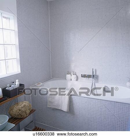 Stock Photo - White bath in modern bathroom with grey mosaic tiled walls. Fotosearch