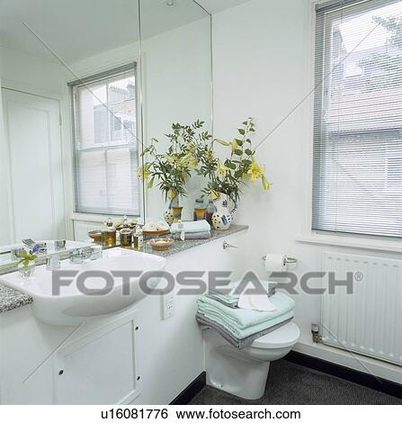 Stock Photograph - White bathroom with sash window and mirrored wall. Fotosearch