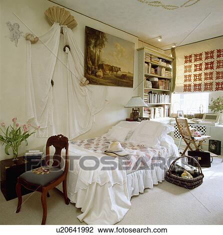 White Bedlinen And Patchwork Quilt On Bed Below White Drapes On
