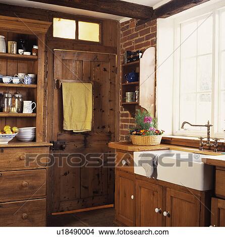 White ceramic sink in fitted wood kitchen with towel on the back of pine door View Large Photo Image Picture - White ceramic sink in fitted wood kitchen with towel on the back of pine door. Fotosearch