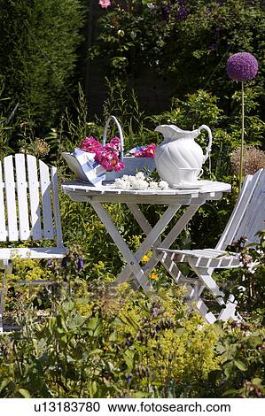 White chairs and table with white jug in country garden in summer View Large Photo Image Stock Image - White chairs and table with white jug in country garden in summer. Fotosearch