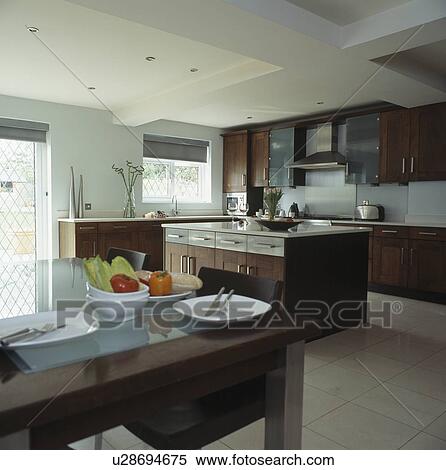 Stock Photography - White crockery on table in modern kitchen with dark wood island unit&#13; &#10; &#13; &#10;. Fotosearch