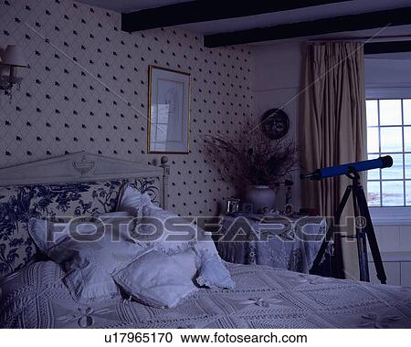 White cushions and crochet bedcover on bed in cottage bedroom with telescope at the window and spotted wallpaper View Large Photo Image Stock Image - White cushions and crochet bedcover on bed in cottage bedroom with telescope at the window and spotted wallpaper. Fotosearch