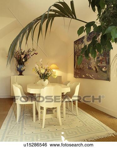 White forties-style chairs and table on cream rug in white dining room View Large Photo Image Stock Photograph - White forties-style chairs and table on cream rug in white dining room. Fotosearch