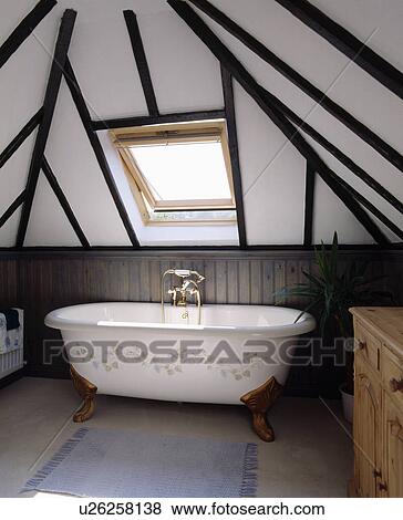 White freestanding clawfoot bath with floral stencil below velux window in beamed attic bathroom View Large Photo Image Stock Photo - White freestanding clawfoot bath with floral stencil below velux window in beamed attic bathroom . Fotosearch