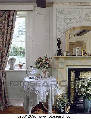 Stock Photograph - White lace cloth on table in traditional living room with stencilled wall. Fotosearch