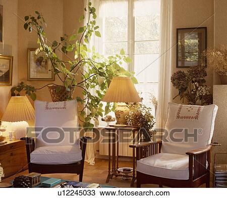 Stock Image - White loosecovers on armchairs in traditional living room. Fotosearch