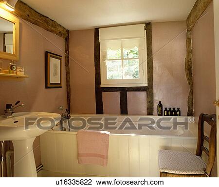 White panelled bath and pedestal basin in beamed pink cottage bathroom with white blind above window View Large Photo Image Stock Image - White panelled bath and pedestal basin in beamed pink cottage bathroom with white blind above window. Fotosearch