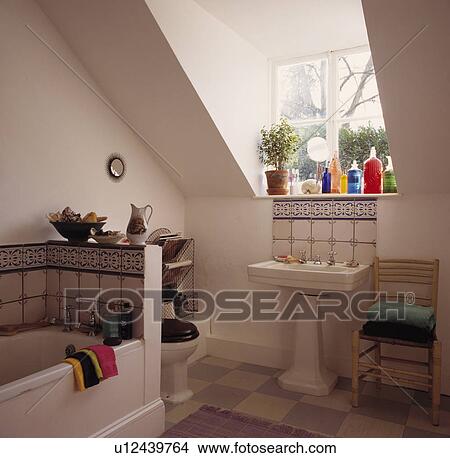 Picture - White pedestal basin below window in white attic bathroom. Fotosearch