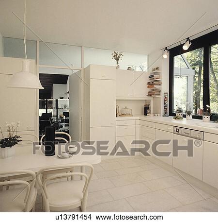Picture - White pendant light over white table and bentwood chairs in modern white kitchen with white floor tiles. Fotosearch