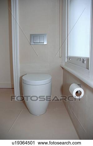 Stock Image - White Philippe Starck toilet in modern beige bathroom. Fotosearch