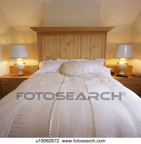 White pillows and duvet on bed with pine headboard in modern bedroom with white lamps on either side of the bed View Large Photo Image Stock Image - White pillows and duvet on bed with pine headboard in modern bedroom with white lamps on either side of the bed. Fotosearch