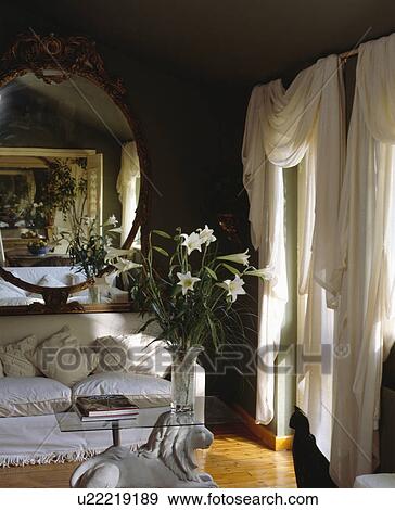 White Sofa And Draped Curtains In Black Living Room Stock Photo