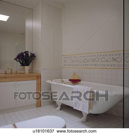 Stock Photo - White tiled architectural bathroom with detail tiles and rolltop bath.. Fotosearch