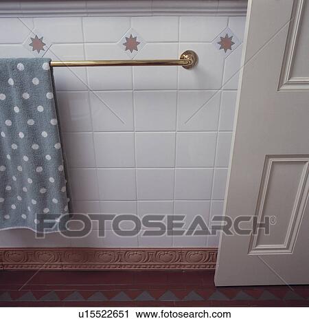 Stock Image - White tiled bathroom detail with brass towelrail and interesting skirtingboard treatment.. Fotosearch