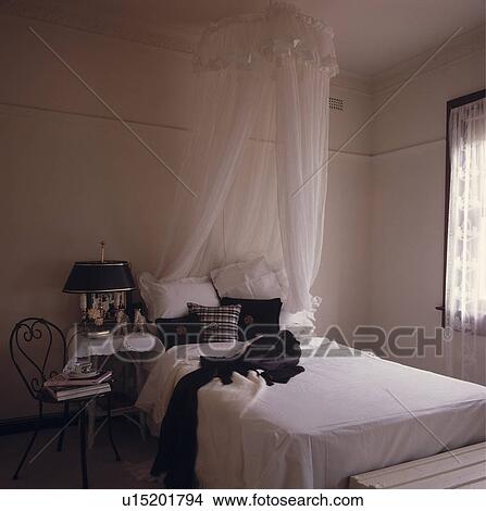 White voile mosquito net above bed with white linen and black pillows in white bedroom View Large Photo Image Picture - White voile mosquito net above bed with white linen and black pillows in white bedroom. Fotosearch