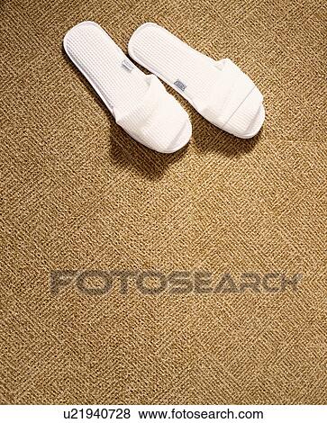 Stock Photo - White waffle cloth slippers on a natural fibre carpet. Fotosearch