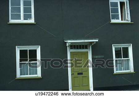 Stock Photograph - White windows and green front door in brown cottage. Fotosearch