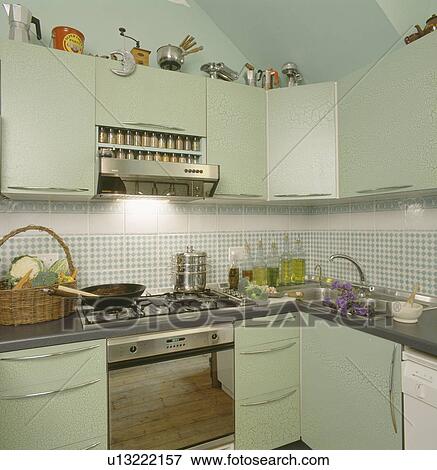 Stock Photo - Wok on hob of stainless steel oven in pastel green modern kitchen. Fotosearch