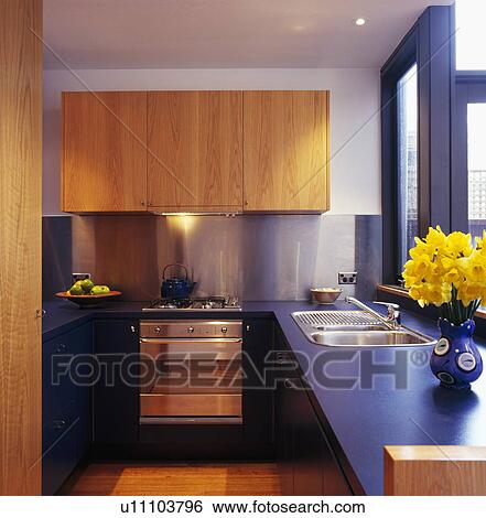 Wood fitted cupboards above stainless steel oven in modern kitchen with blue worktops View Large Photo Image Stock Photograph - Wood fitted cupboards above stainless steel oven in modern kitchen with blue worktops. Fotosearch