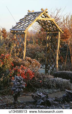 Stock Image - Wooden arch and pergola in country garden in winter. Fotosearch