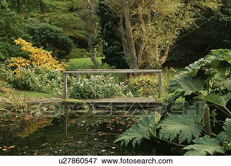 Stock Photo - Wooden bridge over stream in country garden. Fotosearch