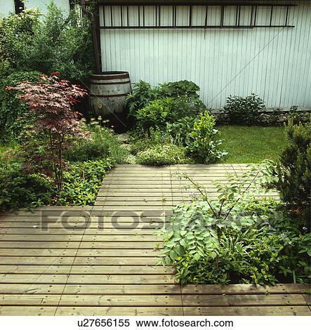 Stock Photography - Wooden decking in small country garden in summer. Fotosearch