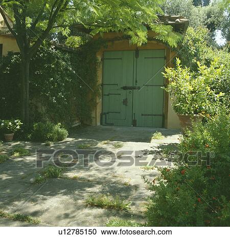 Stock Image - Wooden doors in walled Mediterranean garden. Fotosearch