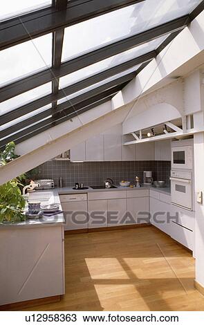 Stock Image - Wooden flooring in modern white attic kitchen with glass roof. Fotosearch