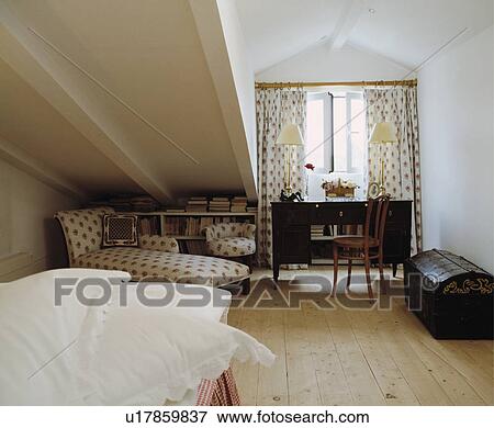 Stock Photo - Wooden flooring in white attic bedroom with floral chaiselongue and antique chest. Fotosearch
