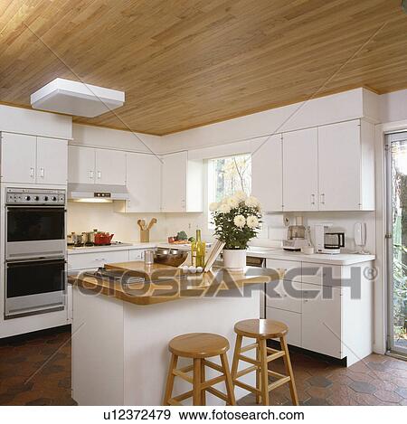 Wooden stools at island unit with wooden worktop in modern white kitchen with wooden ceiling View Large Photo Image Stock Photo - Wooden stools at island unit with wooden worktop in modern white kitchen with wooden ceiling. Fotosearch